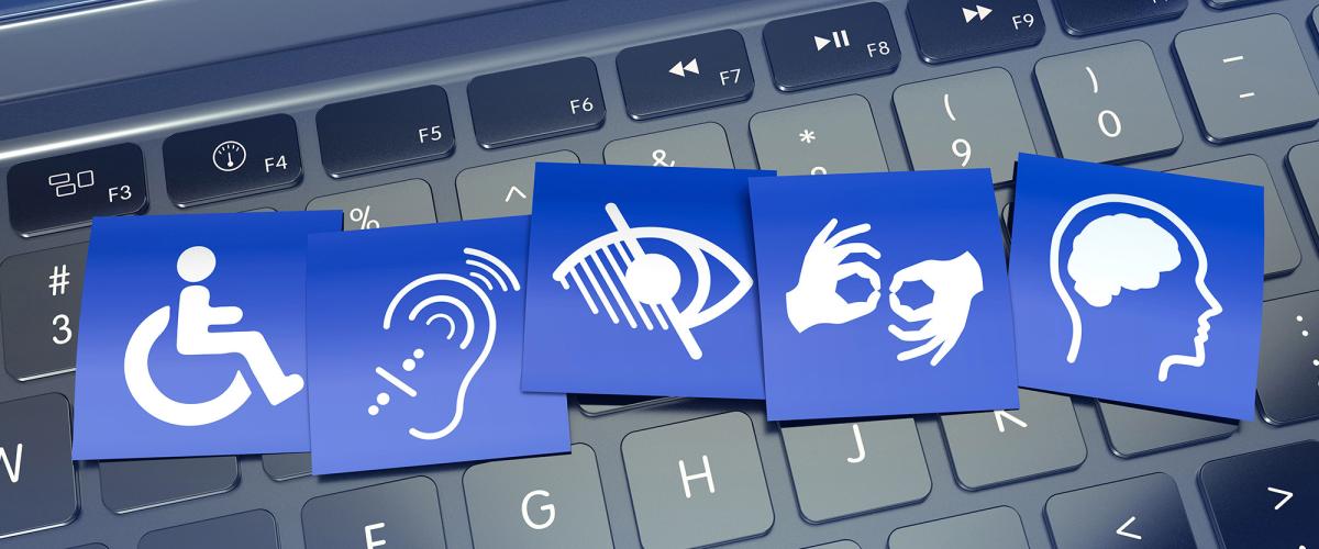 Blue cards with symbols of accessibility needs on top of black keyboard.