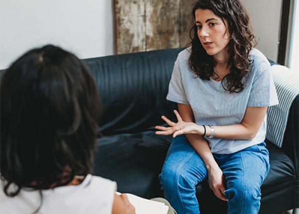 A person sitting on a couch talking to another person.