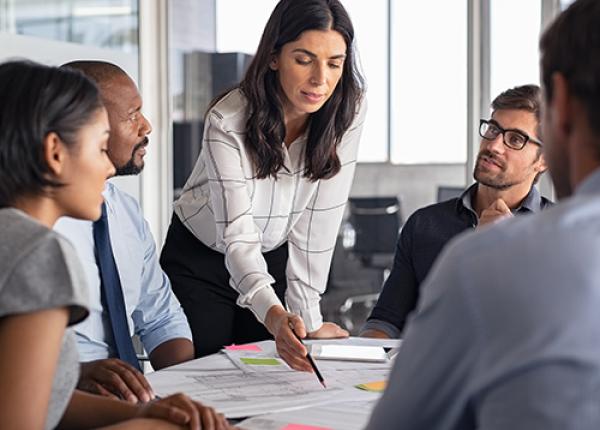 A person is talking to a group of people at a conference table.