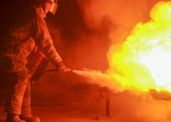 A firefighter using a fire extinguisher to extinguish a fire.