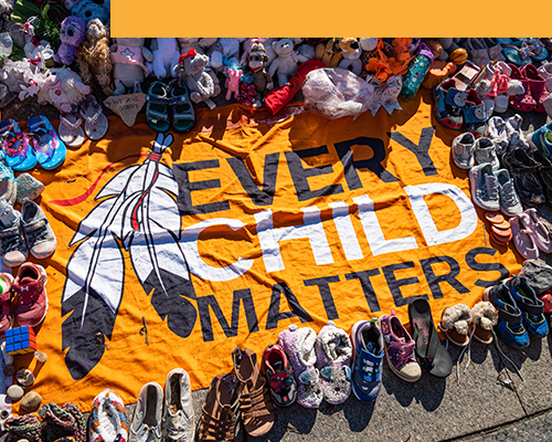 Every Child Matters banner surrounded by children's shoes and toys. They represent First Nations children who died in residential schools.