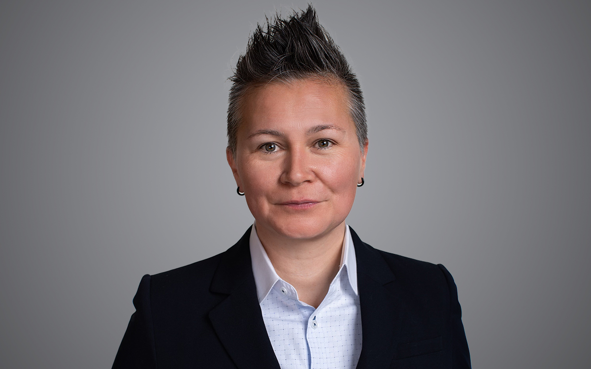 Head and shoulders photo of woman with spiked hair in dark jacket and white shirt.