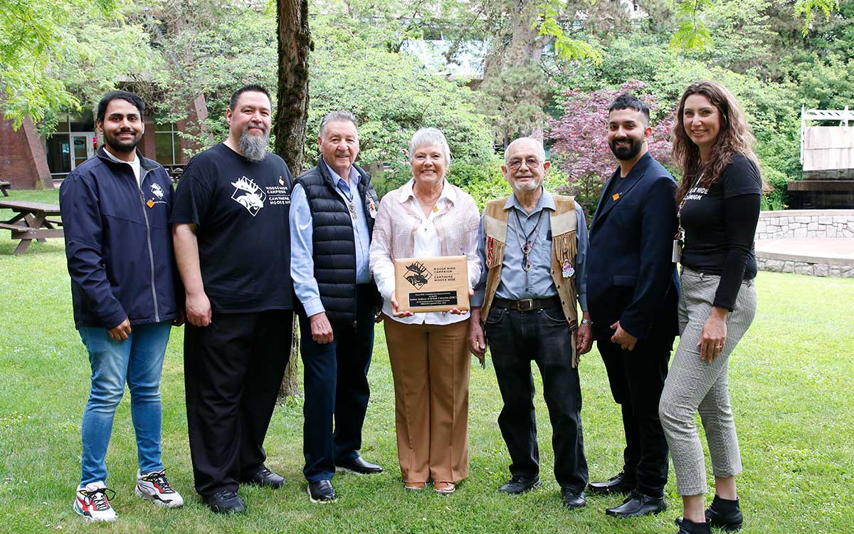 Five men and two women - JIBC Office of Indigenization staff and Elders-In-Residence and Moose Hide Campaign staff - pose with plaque.