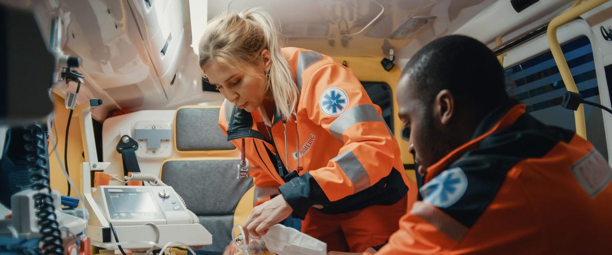Two paramedics working on patient in back of ambulance.
