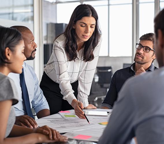 A person is talking to a group of people at a conference table.