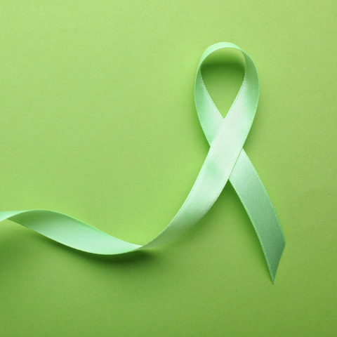 A green awareness ribbon on a green background