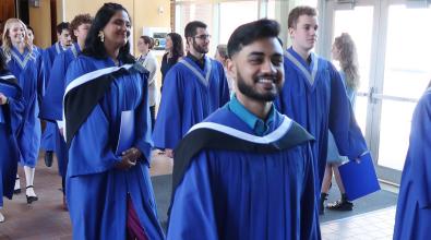 JIBC grads in blue gowns leaving the convocation ceremony.