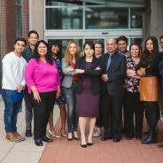 Diverse group of people stand in front of building.