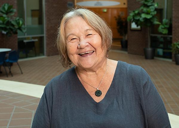 Woman with short bobbed hair wearing dark grey V-necked shirt.